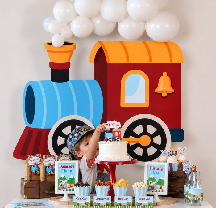 Toddler in a conductor hat reaching for his cake at a Chugga Chugga Two Two train birthday party, with train backdrop, balloon garland, and snack table