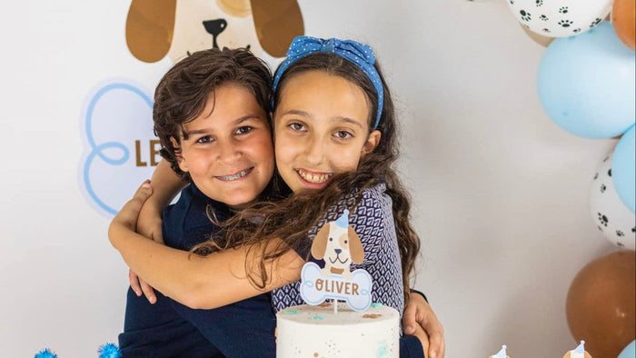 Kids celebrating a blue puppy dog themed birthday party with a personalized cake and balloon garland
