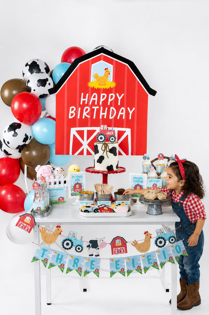 A girl smiling at a decorated on-the-farm birthday party dessert table