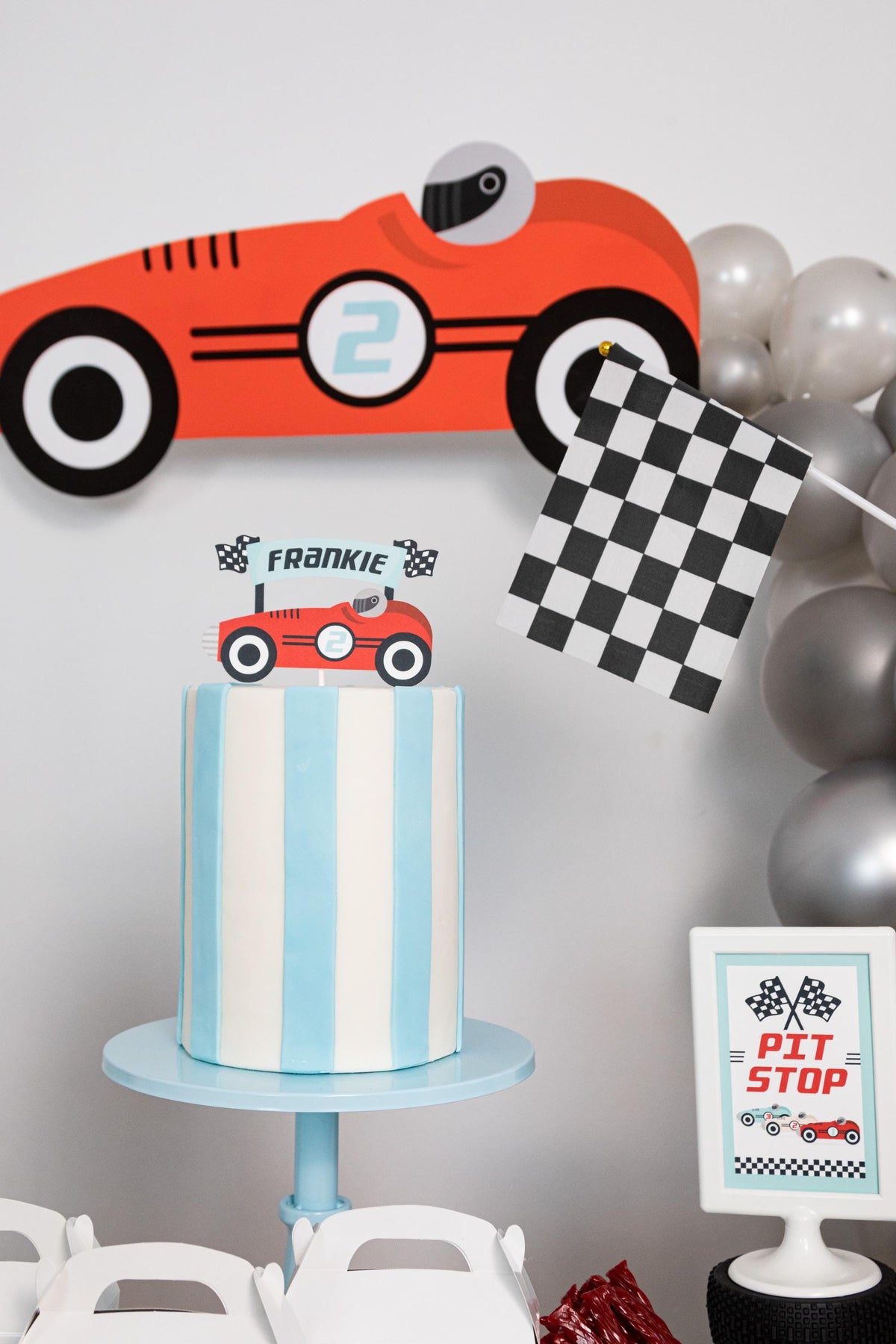 Pit Stop Vintage Race Car Sign - framed "Pit Stop" sign on a tire stand next to donuts, checkered flag and race car favor boxes